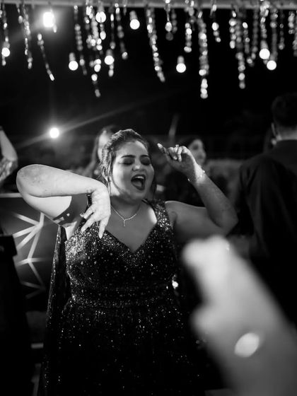 A high-energy black and white photo of a guest dancing and singing along at the Sangeet party.