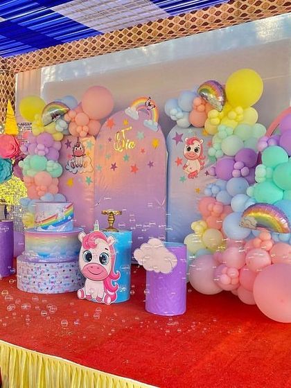 A unicorn-themed stage on a red carpet, decorated with pastel balloon arrangements and cute unicorn character props.