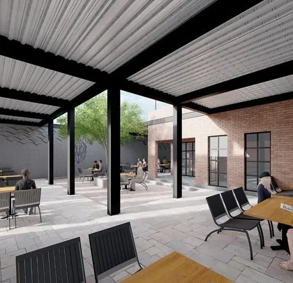 This view from under the covered patio shows the relationship between the indoor and outdoor spaces. The use of exposed brick walls and large window frames helps connect the different areas of the cafe seamlessly.