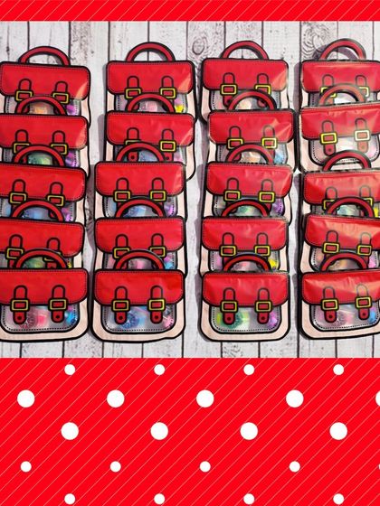 A large order of the red schoolbag-shaped favor bags, all filled and ready for a party.