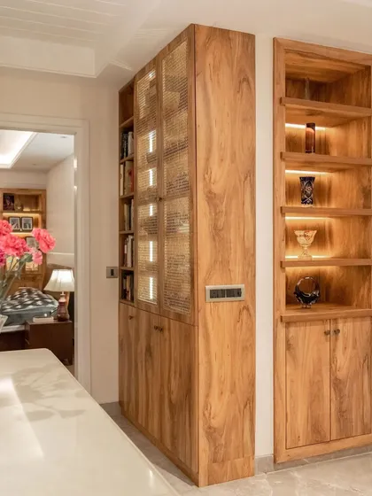 We designed these custom wooden cabinets for a client who is an avid reader. The unit on the left features rattan-fronted doors with backlighting for a soft glow, while the open niche on the right is perfect for displaying treasured items.