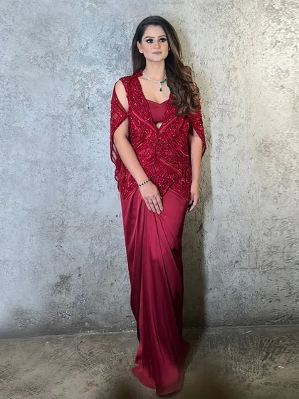 A client wearing an enchanting red cape paired with a draped bottom, a stunning ensemble that redefines festive elegance.