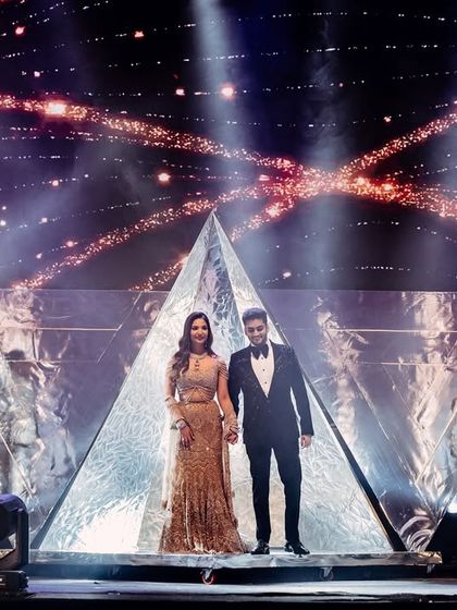 A powerful shot of the couple's final pose during their grand entry. Standing on a pyramid prop amidst pyrotechnics and dramatic lighting, this moment was designed to be a lasting, iconic image.