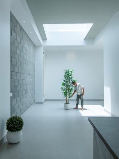 Another perspective of the minimalist corridor, showing its connection to a kitchen or bar area. The design emphasizes clean, uncluttered space and the powerful effect of natural light.