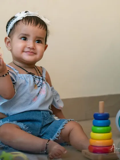 A happy baby girl playing with her toys, this shot captures her bright smile and joyful spirit.