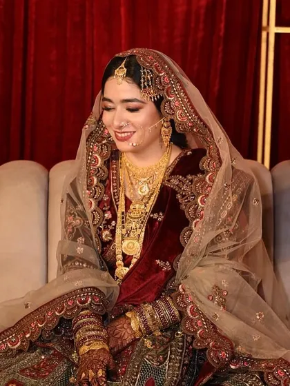 A full shot of the bride seated, looking regal in her velvet outfit. The makeup ties the entire look together with elegance.