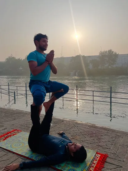 The 'throne' pose in acroyoga, where the flyer sits gracefully on the base's feet, framed by the rising sun.
