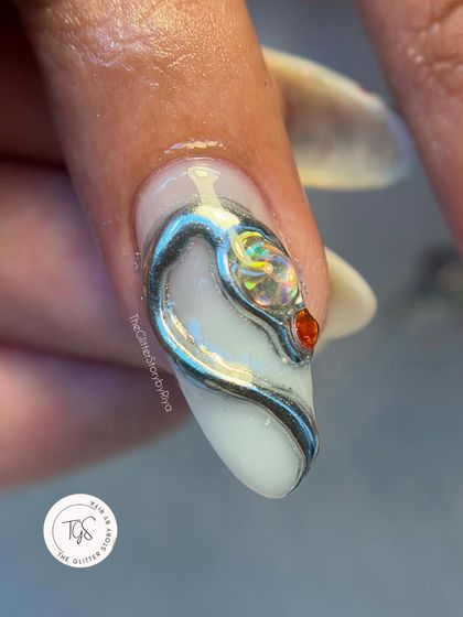 A macro shot of a single nail with a sculpted silver snake design. The intricate details and the tiny red crystal eye make this a true statement piece of nail art.