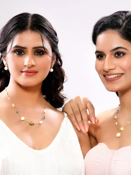 A shot of two models wearing pearl and gemstone necklaces. The friendly interaction between them creates a relatable, lifestyle feel for the brand.