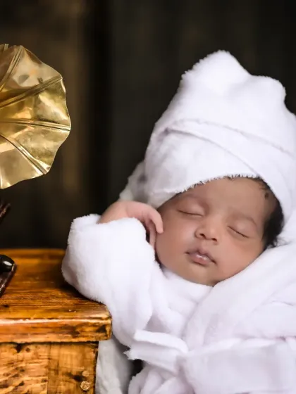 A close-up of a newborn in a spa-themed setup, complete with a tiny bathrobe and a relaxed pose. It's a humorous and adorable take on newborn photography.