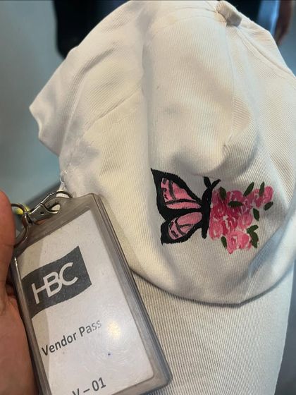 My vendor pass for the HBC event, resting on a cap I painted with a butterfly and flowers. It was a day full of art and inspiration.