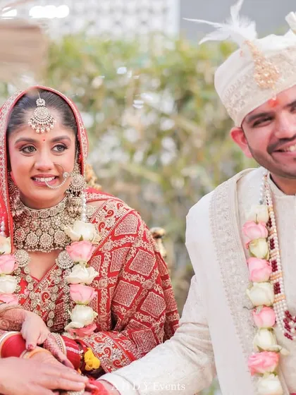 The joy of a wedding ceremony, captured perfectly. This candid moment shows the couple sharing a smile under a beautifully decorated floral mandap, highlighting the happiness we help create.