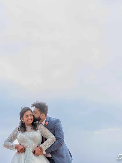 A romantic portrait with the couple set against a wide, open sky. The use of negative space gives the image a light, airy, and minimalist feel.