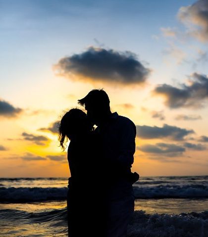 An intimate kiss on the beach, silhouetted against the evening sky. This is a classic romantic shot that perfectly captures the love between the couple.