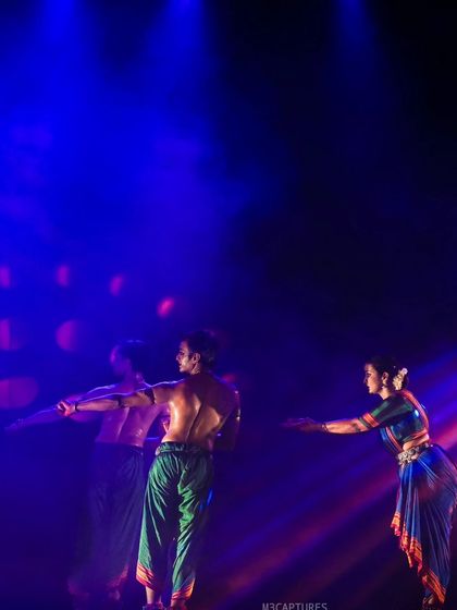 A scene from 'Nagamandala' with dramatic, colorful lighting. The lighting design is integral to the storytelling, shifting to reflect the changing emotions of the narrative.