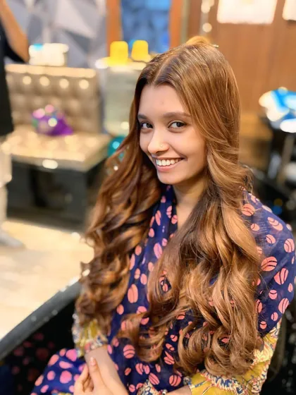 A happy client showing off her new long balayage colour. The soft, sun-kissed highlights blend seamlessly with her natural hair, and the loose curls complete this gorgeous transformation.