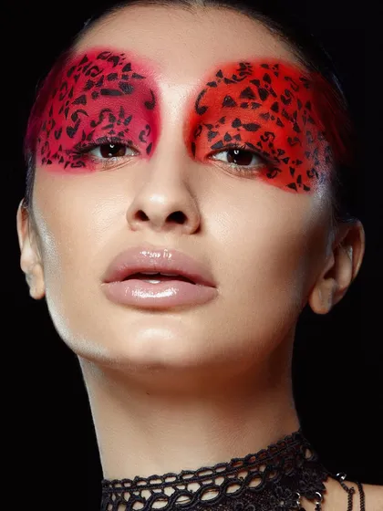 A creative and abstract look with a red leopard-print stencil design over the eyes, showcasing advanced techniques.