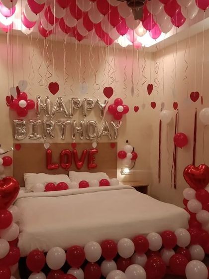 This is a complete room decoration for a birthday, using a dense arrangement of red and white balloons on the ceiling, floor, and in pillars to create an immersive and festive experience.