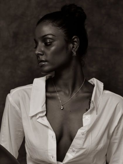 A soft and pensive black and white portrait. The lighting is gentle and creates a beautiful, classic mood.