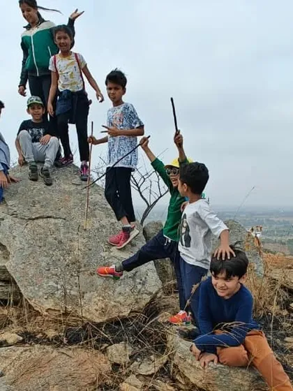 The triumphant feeling of reaching the top. During one of our community treks near Bangalore, children work together, overcome challenges, and build resilience, all while surrounded by the beauty of the great outdoors.