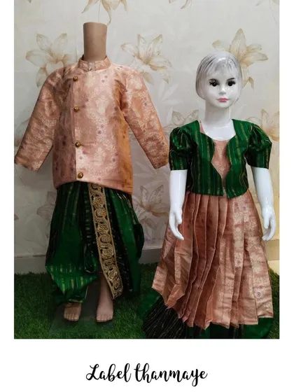 This is a brother and sister ethnic wear set, perfect for festivals or traditional functions. The boy's outfit features a peach Banarasi silk kurta with a green dhoti, complementing the girl's matching Pattu pavadai.