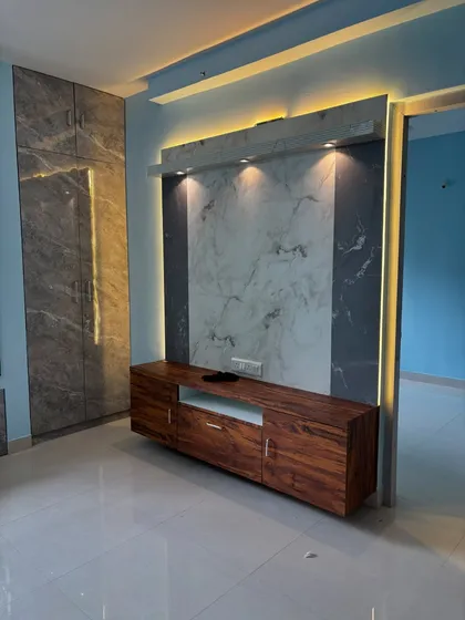 Here is a look at a modern living room featuring a floating TV console we built. The design combines a rich wood grain finish with a sophisticated marble-look backdrop. We integrated both ambient backlighting and focused spotlights to create a dramatic effect and highlight the textures.
