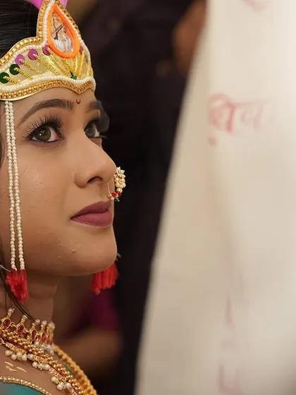 A quiet moment of reflection for the bride before the ceremony. This close-up shows the detailed eye makeup and the traditional mundavalya, essential parts of the bridal look.