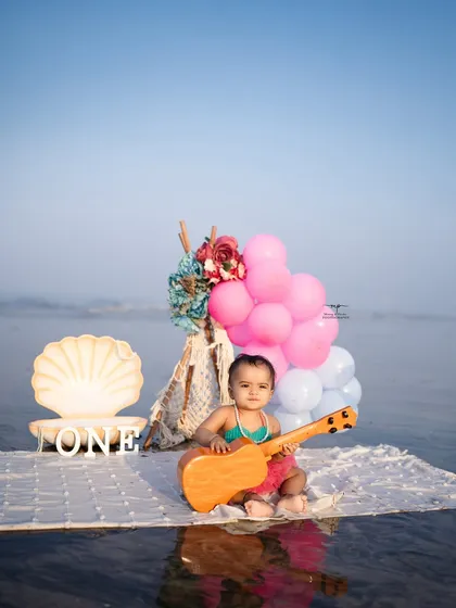 The little mermaid poses with her ukulele, with the calm sea behind her. The soft lighting and clear blue sky make the colors of the setup pop.