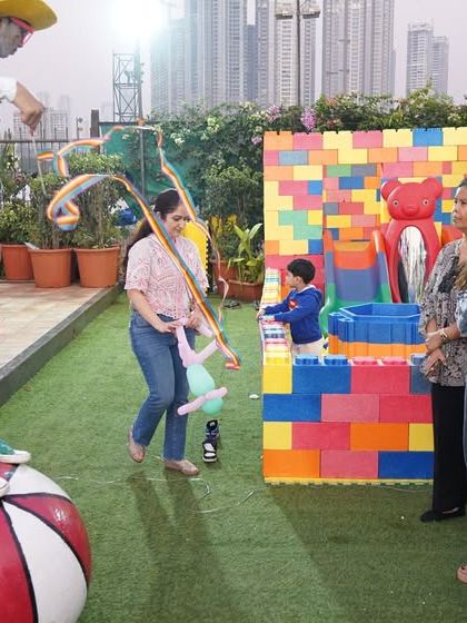 A wide shot of the outdoor party space, showing guests enjoying the various activities and performances.
