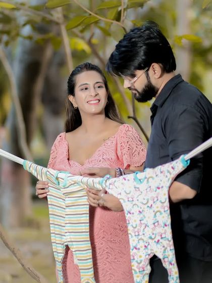 A playful and sweet shot for an outdoor couple's shoot. The parents-to-be hold up a line of tiny baby clothes, dreaming of the days to come.