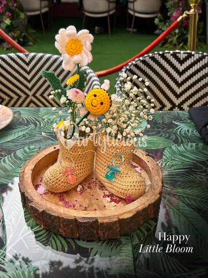 Happy little bloom. A charming and unique centerpiece featuring crocheted baby booties filled with baby's breath.
