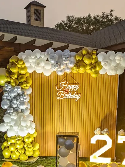 A detailed view of the balloon arch for the outdoor birthday party, showcasing the mix of gold, silver, and white balloons.