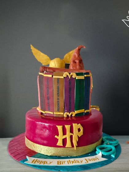 A magical two-tier Harry Potter cake, featuring a stack of spellbooks, the Sorting Hat, and the Golden Snitch. A truly spellbinding creation for a dedicated fan.