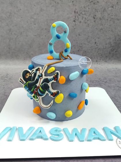 A rock climbing cake for an adventurous 8-year-old. This cake is designed to look like a climbing wall, with a ninja climber making their way to the top.