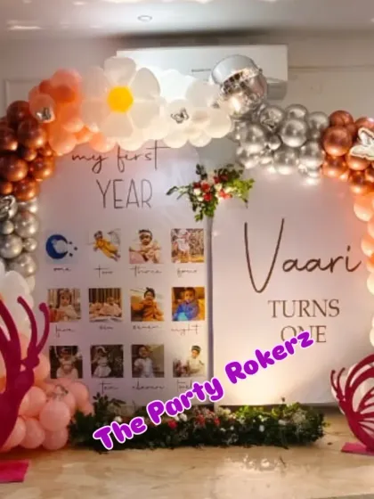 A clear shot of the "My First Year" photo backdrop, surrounded by a beautiful balloon arch with daisy and butterfly details. It's a heartwarming centerpiece for a first birthday.