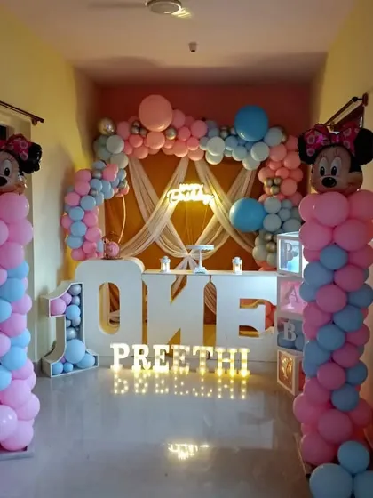A Minnie Mouse themed first birthday party set up in a hallway. The decoration features large 'ONE' letters and Minnie Mouse balloon pillars.
