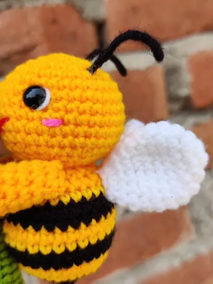 A custom-made keychain featuring a happy little bee holding a handmade hydrangea flower. The level of detail in the tiny petals was a fun challenge.