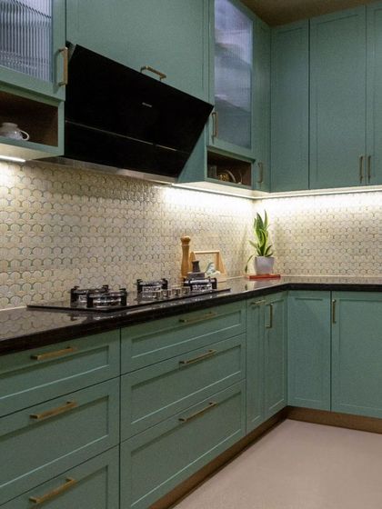 The tranquil green kitchen, designed to maximize storage and functionality. A beautiful floral backsplash and classic fluted glass elevate the overall look with a touch of sophistication.