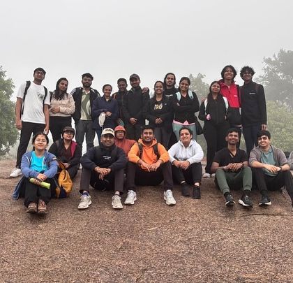 A large group poses on the misty rocks of a sunrise trek.