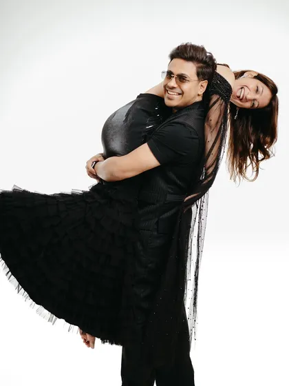 A playful studio portrait against a clean white background. The man joyfully lifts his laughing partner, demonstrating how a minimalist setting can amplify the couple's fun-loving energy and create a fresh, modern pre-wedding picture.