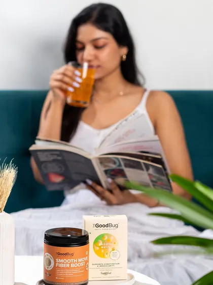 A lifestyle shot showing a model relaxing with a book while drinking The Good Bug's fiber supplement, associating the product with calm and self-care.