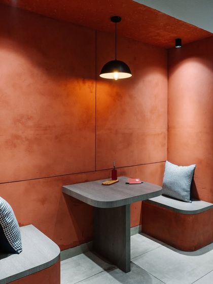 A close-up of the terracotta-colored breakout nook, showing the textured walls and simple, functional furniture.