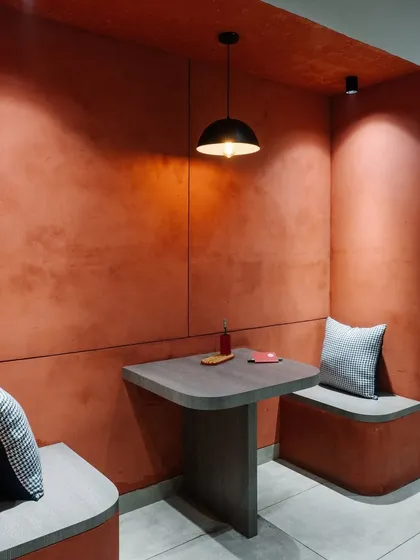 A close-up of the terracotta-colored breakout nook, showing the textured walls and simple, functional furniture.