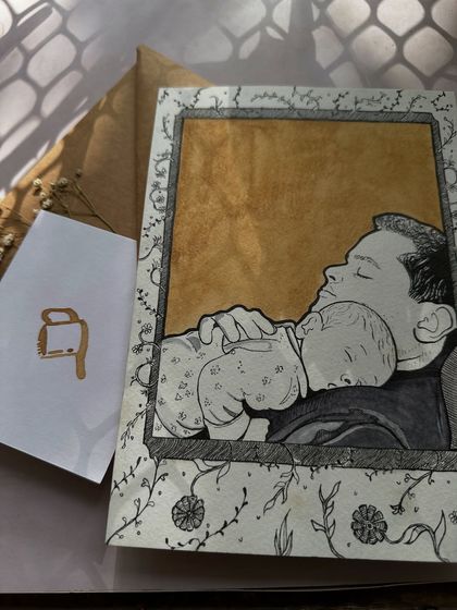 A tender moment between a father and his baby, captured in a custom illustration. The piece is framed with a floral border and set against a warm coffee-painted background.