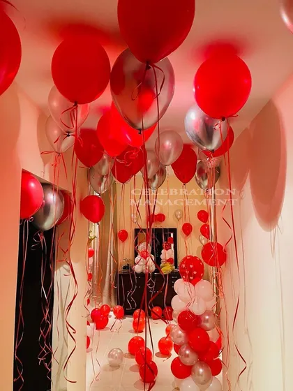 I filled this entire hallway and room with red and silver balloons to create an immersive celebration experience. It builds anticipation as you walk through the balloon-filled corridor to the main surprise.