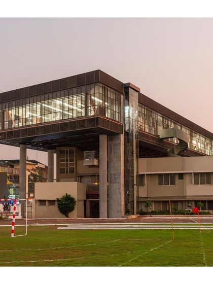 The building at dusk, with the interior lights revealing the activity within. The design balances the need for functional office space with the creation of a strong architectural identity.