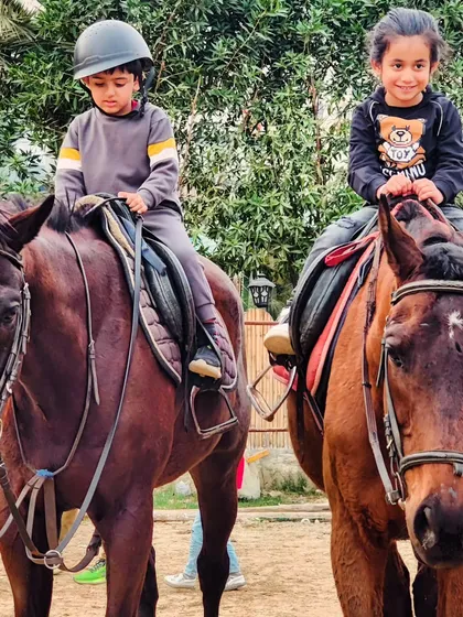 Two young riders pose confidently on their horses. We offer a great environment for sibling photoshoots and capturing their shared interest in horse riding.