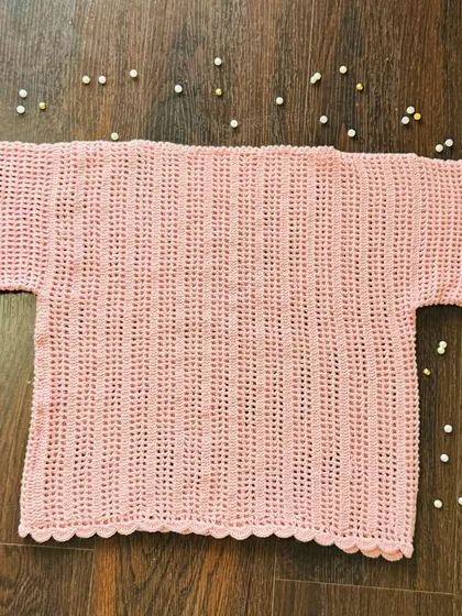 A flat-lay view of the baby pink kids' top. You can see the delicate scalloped hem and the consistent vertical stitching I use to create this simple, airy design.