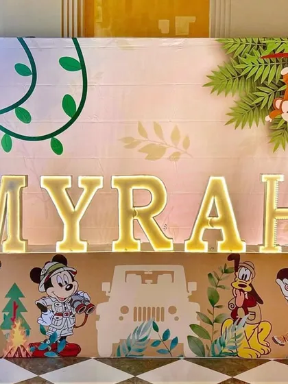 The beautifully crafted light-up name sign for "Myrah," featuring jungle leaves and safari character details. This personalized element makes the birthday girl feel extra special.
