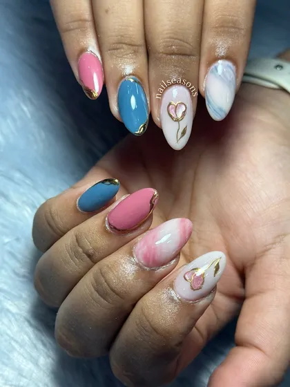 A playful and colorful design with a mix of pink and blue nails, marble effects, and hand-painted floral details.